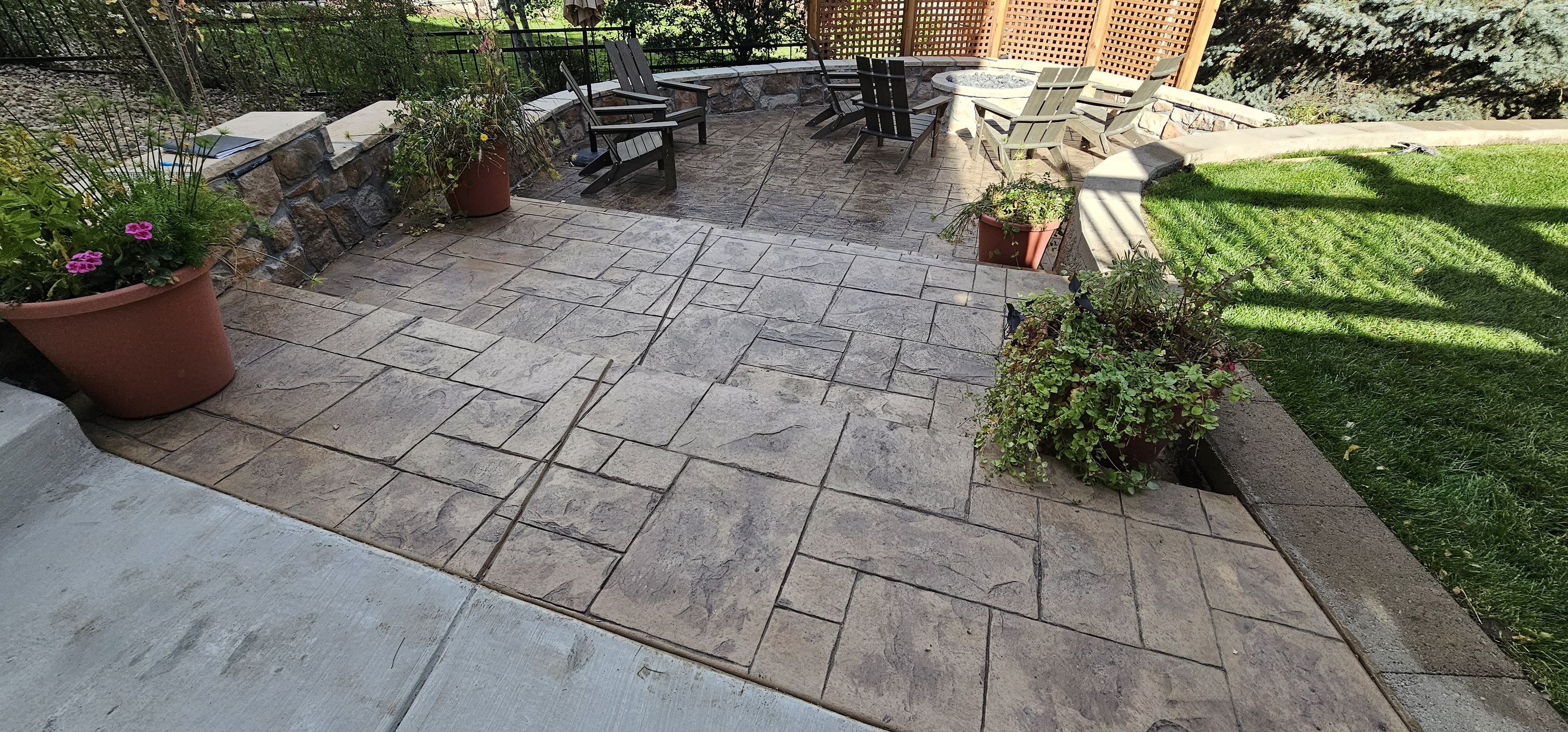 Stamped concrete patio with a stone pattern, seating, and planted borders.